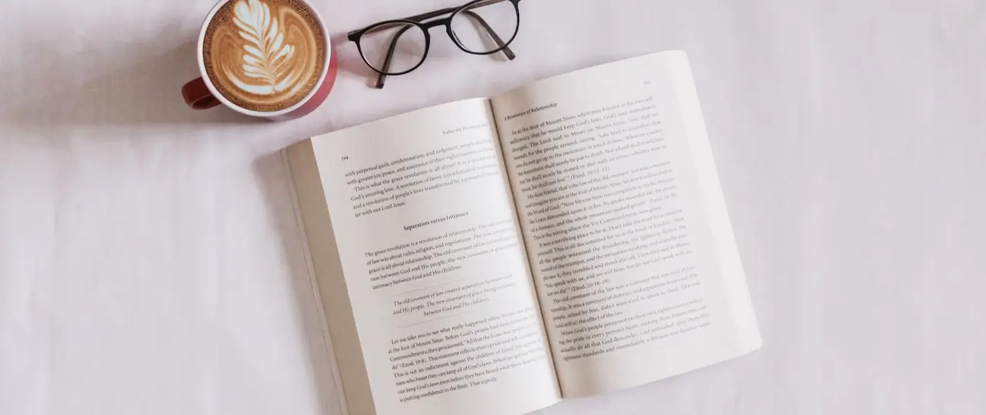 Open book with pages fanned on a table beside a pen