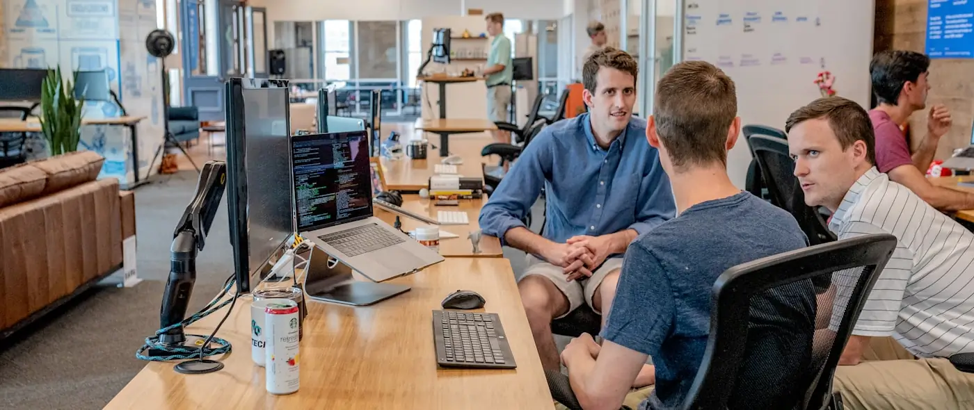 Small team collaborating around a laptop in a bright office