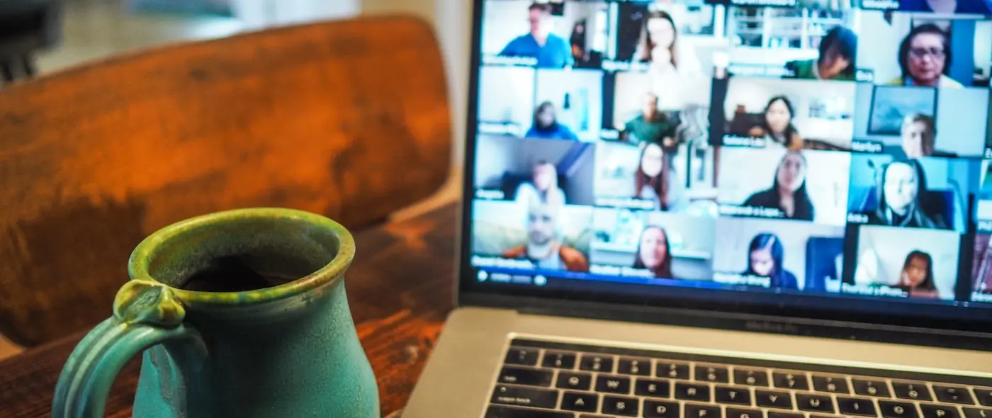 Person working remotely with a laptop and coffee in a home office