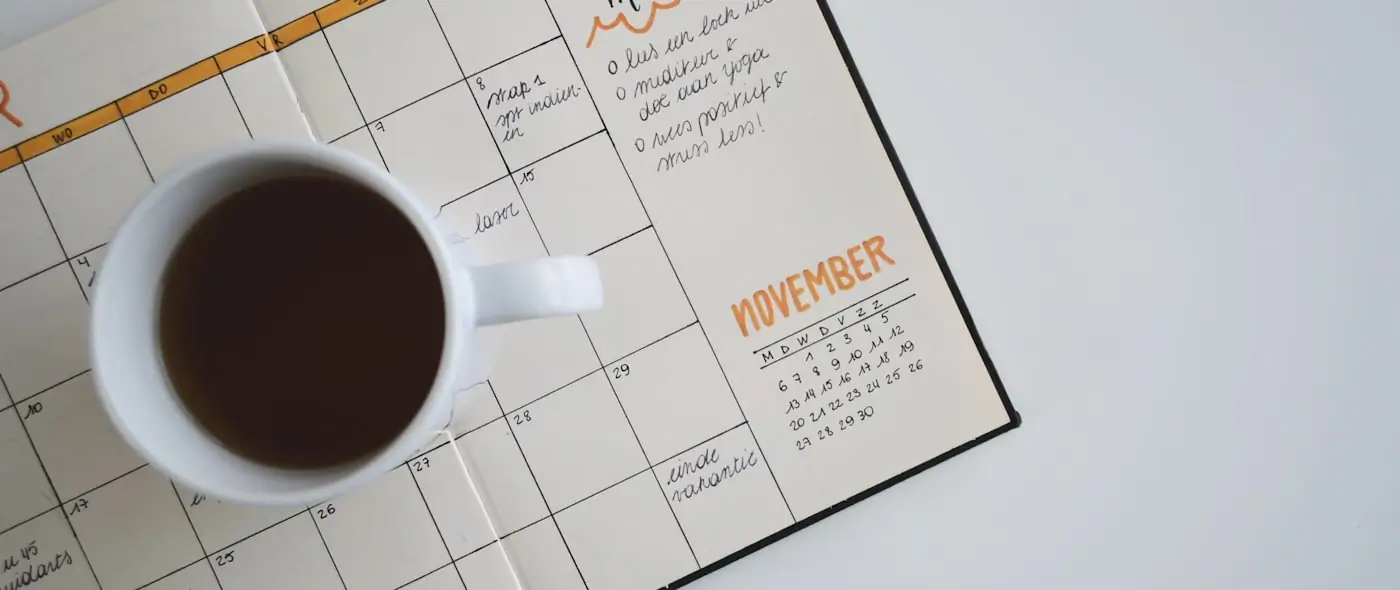 Flat lay of a planner and calendar on a wooden desk