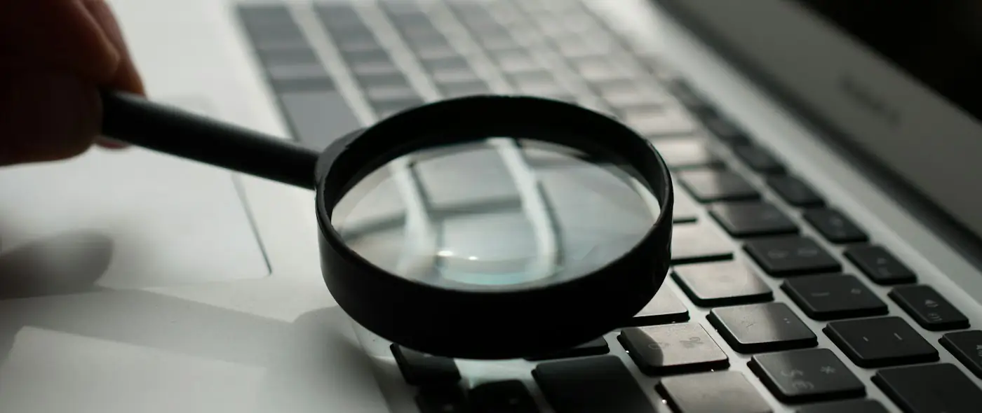 Magnifying glass resting near a gray laptop computer