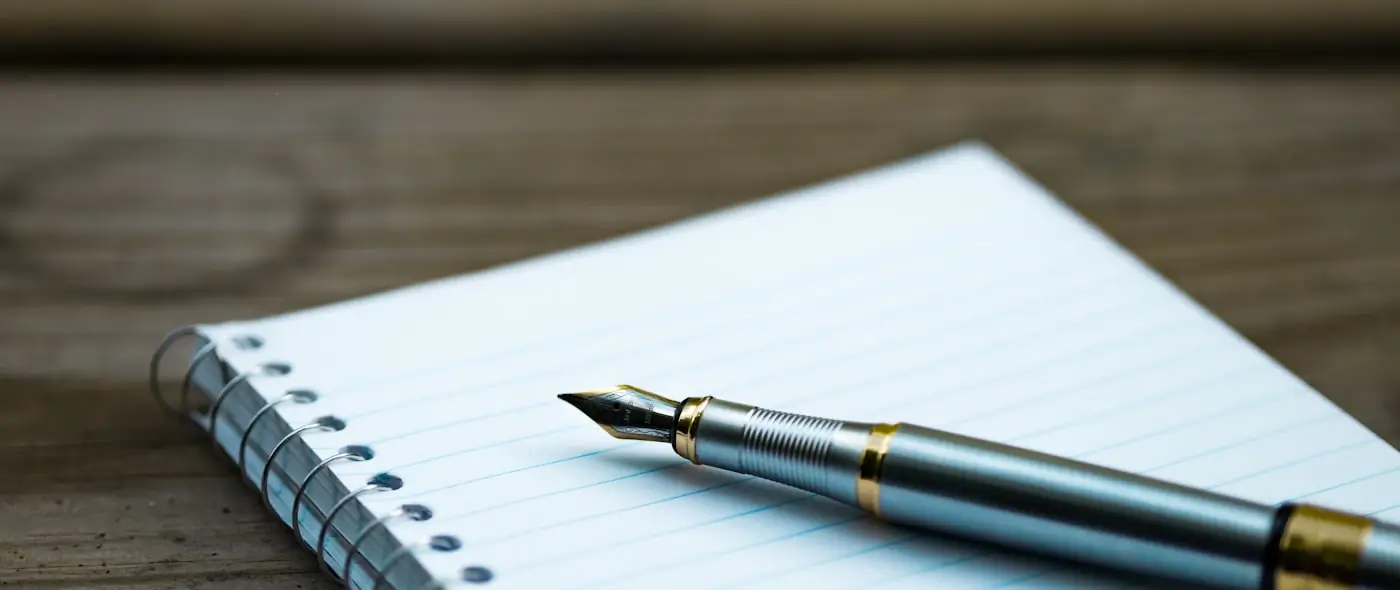 Fountain pen resting on an open spiral notebook