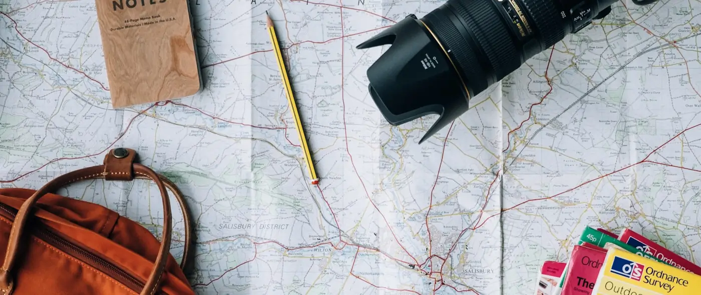 Travel map and notebook laid out for trip planning on a table