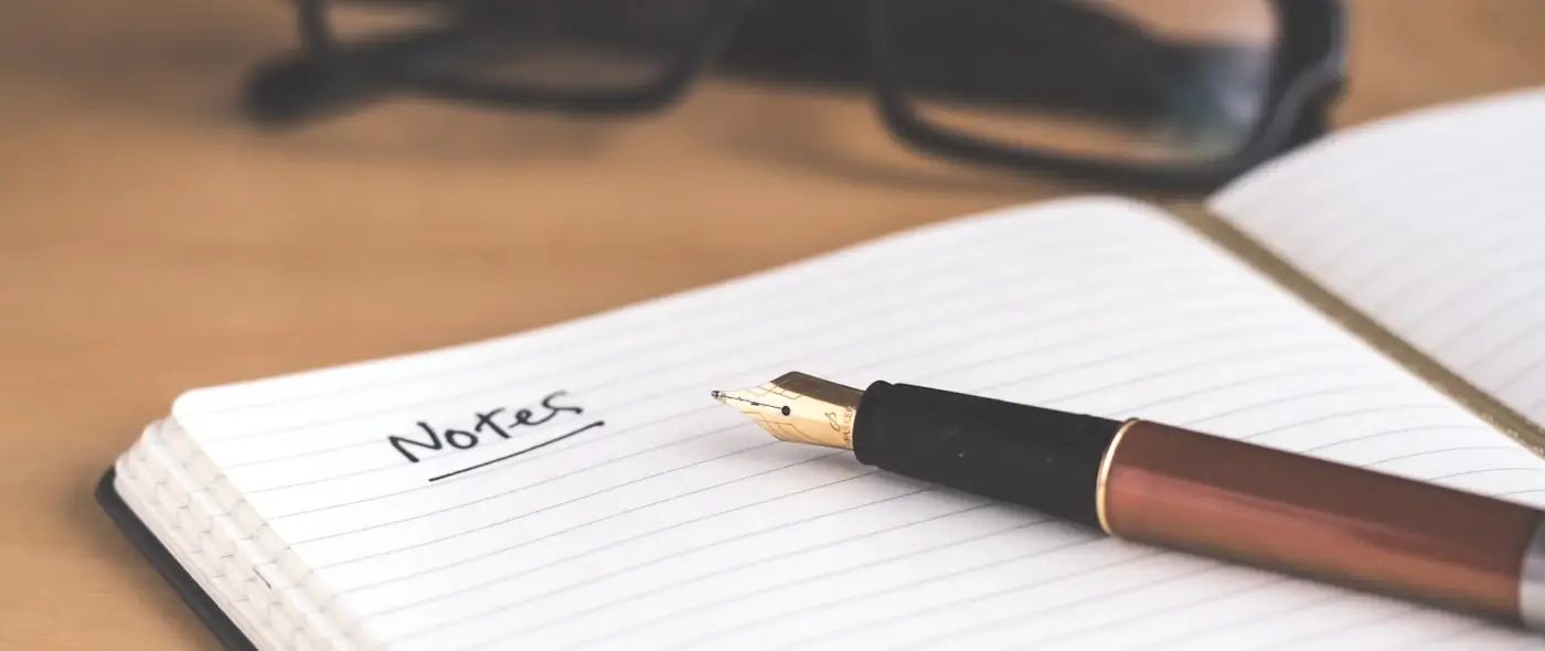 Open notebook and pen on a wooden desk with soft natural light