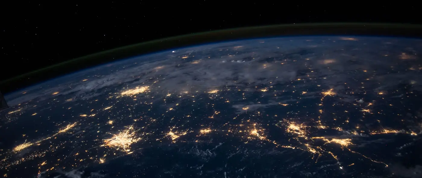 Earth from space at night with networks of city lights forming visible connections across continents
