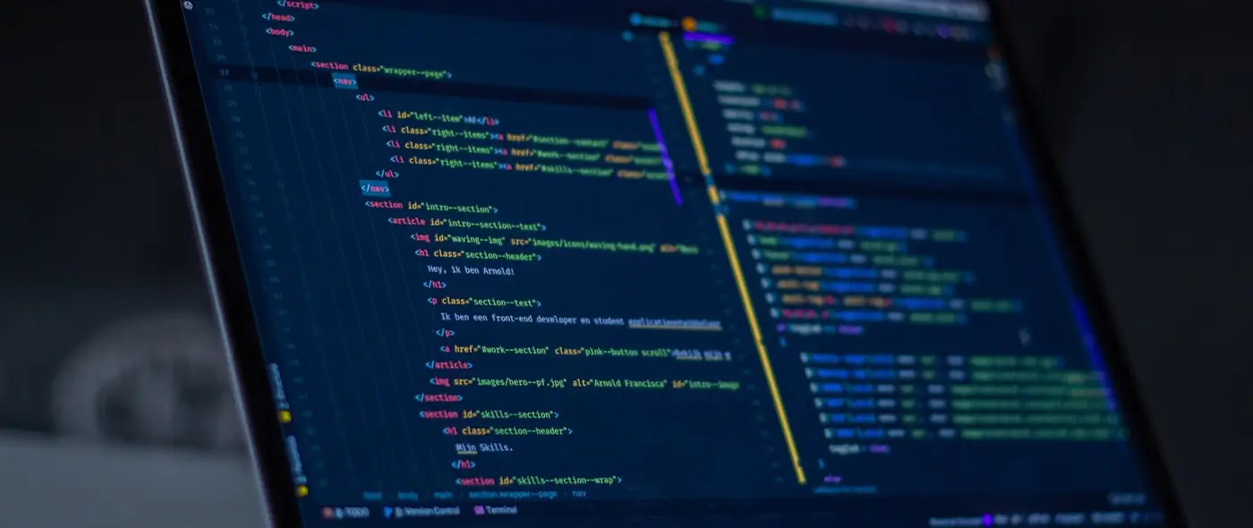 Lines of code on a laptop screen in a dark room with warm ambient lighting